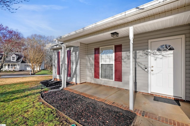 doorway to property featuring covered porch and a yard