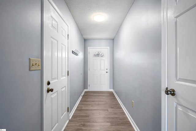 doorway to outside with a textured ceiling, baseboards, and dark wood-style flooring