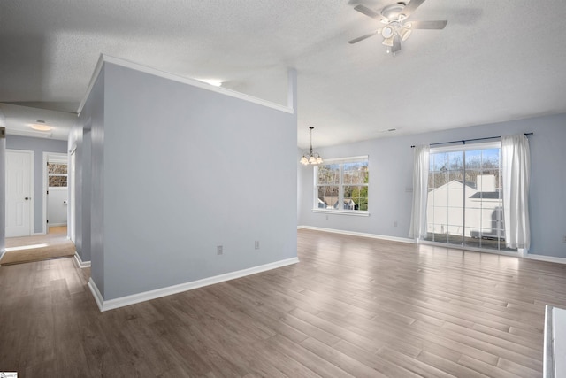 unfurnished living room featuring lofted ceiling, ceiling fan with notable chandelier, a textured ceiling, wood finished floors, and baseboards