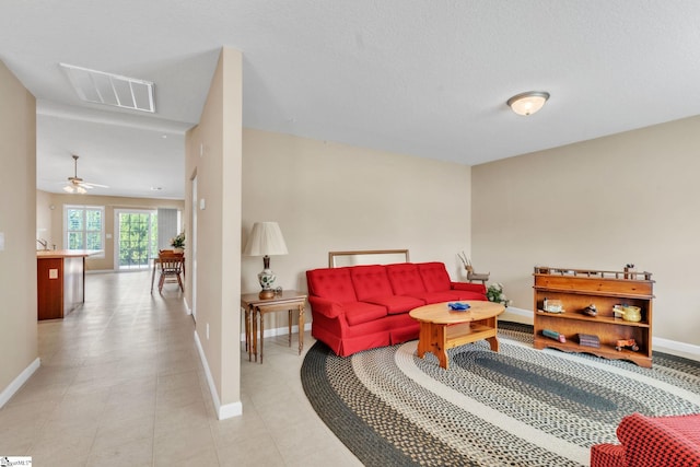 living area featuring visible vents, baseboards, a textured ceiling, and light tile patterned flooring