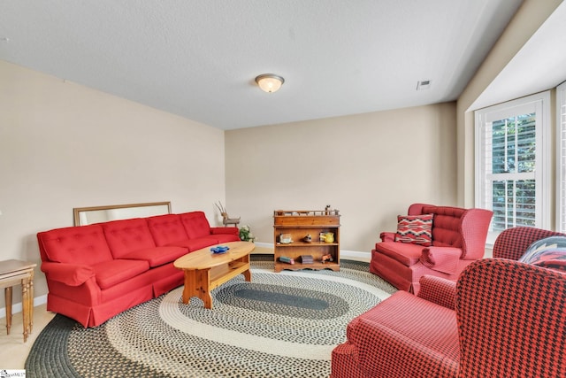 carpeted living room with visible vents, baseboards, and a textured ceiling