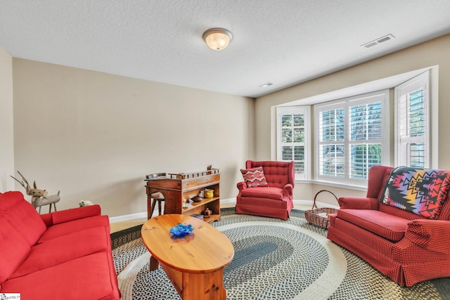 carpeted living area featuring visible vents, a textured ceiling, and baseboards