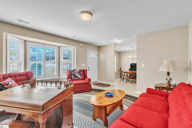 living area featuring visible vents, baseboards, a notable chandelier, and a textured ceiling