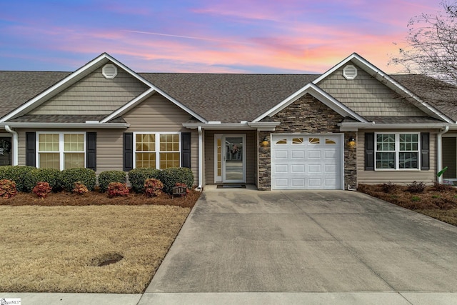 view of front of property with stone siding, driveway, a shingled roof, and a garage