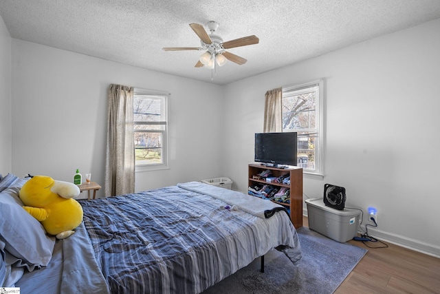 bedroom with multiple windows, a textured ceiling, and wood finished floors