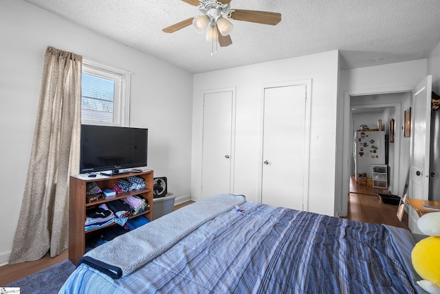 bedroom with heating unit, a textured ceiling, ceiling fan, and wood finished floors