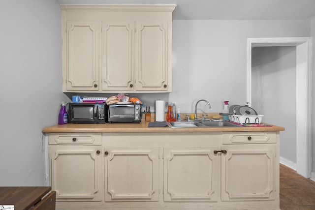 kitchen featuring light countertops, cream cabinetry, and a sink