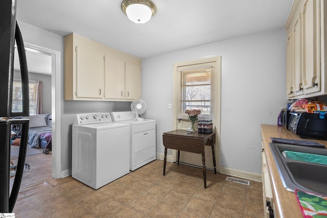 laundry room with a sink, visible vents, baseboards, and washing machine and clothes dryer