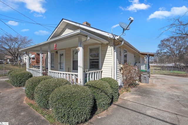 view of front of house featuring fence, covered porch, and a chimney