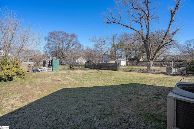 view of yard with central AC and fence