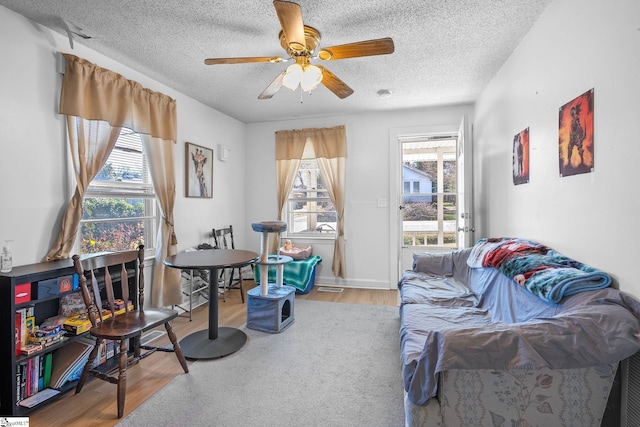 interior space with ceiling fan, wood finished floors, baseboards, and a textured ceiling