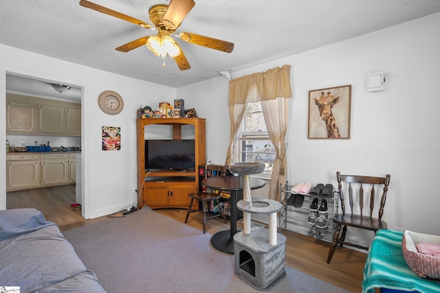 living area with dark wood-style floors, baseboards, a textured ceiling, and ceiling fan