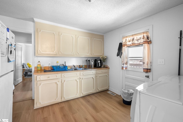 kitchen featuring cream cabinetry, washer and dryer, and light wood-type flooring