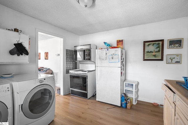 clothes washing area featuring visible vents, laundry area, light wood-style flooring, washer and dryer, and a textured ceiling