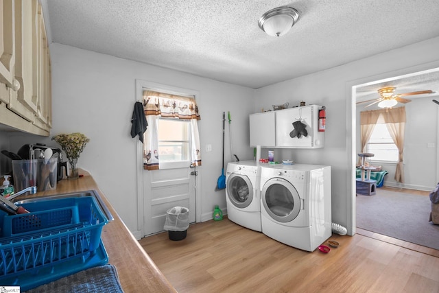 laundry area featuring washer and dryer, light wood-style flooring, cabinet space, and a healthy amount of sunlight