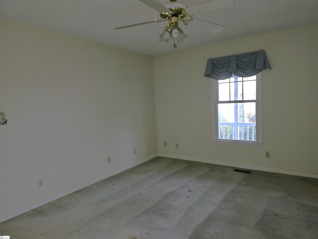 carpeted spare room with visible vents, baseboards, and a ceiling fan