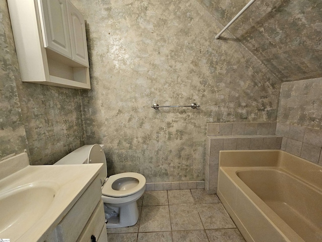 bathroom featuring toilet, a tub, tile patterned flooring, baseboards, and vanity