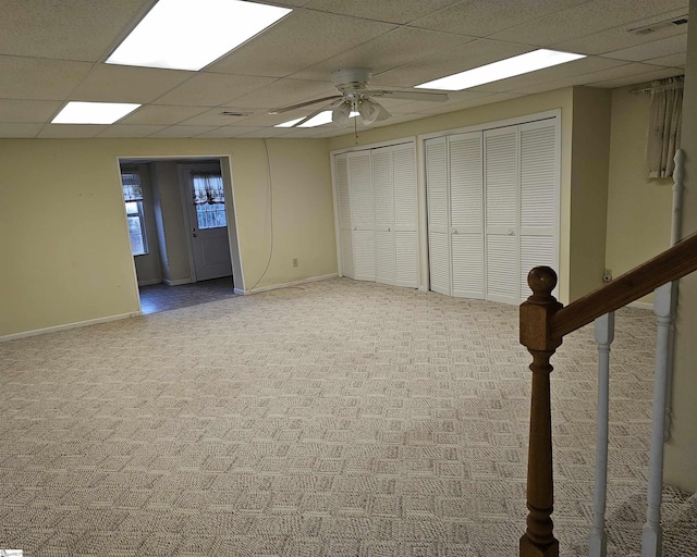 basement featuring carpet, baseboards, visible vents, ceiling fan, and a paneled ceiling