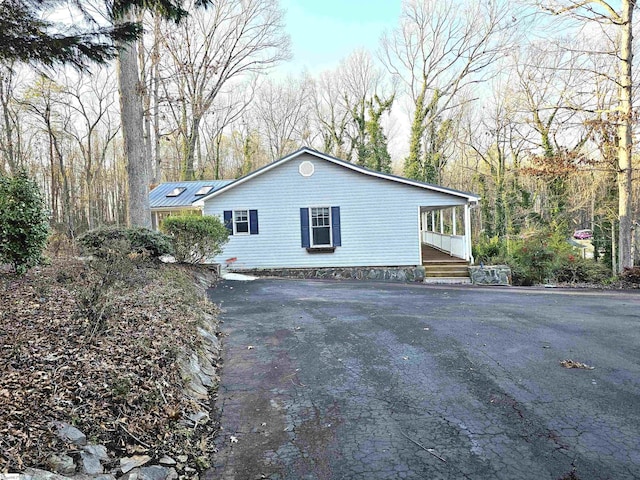 view of home's exterior featuring covered porch, driveway, and metal roof