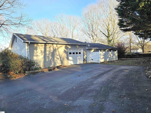 view of side of home featuring driveway, a garage, and fence