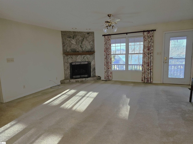 unfurnished living room featuring a stone fireplace, baseboards, and carpet floors