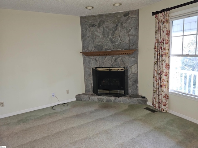 unfurnished living room with carpet, a fireplace, visible vents, and a textured ceiling