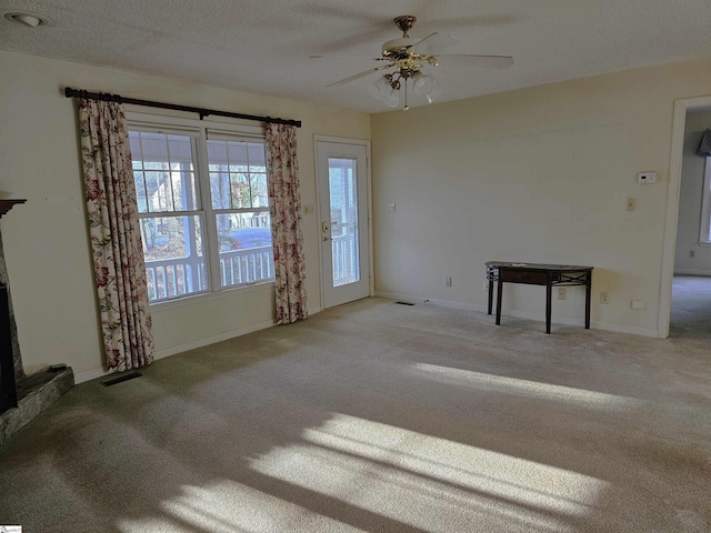 unfurnished living room featuring carpet flooring, visible vents, a ceiling fan, and baseboards