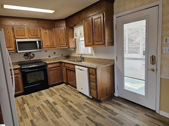 kitchen featuring a sink, white appliances, light wood-style flooring, and brown cabinetry