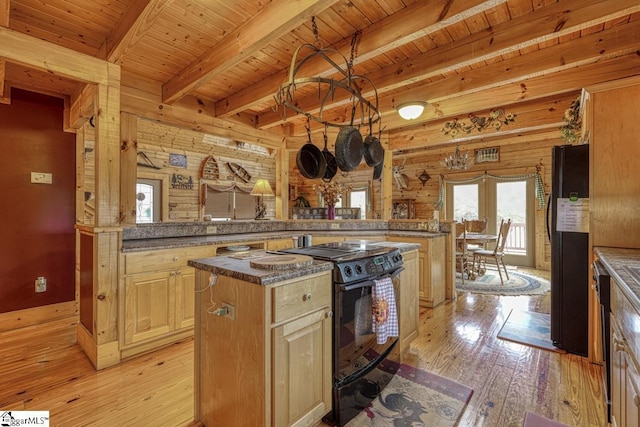 kitchen featuring a center island, beamed ceiling, wood walls, light wood-style flooring, and black appliances