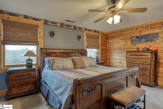 bedroom with visible vents, light carpet, wooden walls, and a ceiling fan