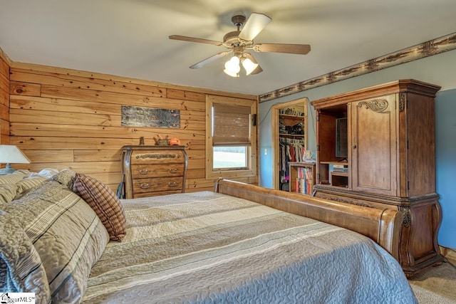 carpeted bedroom featuring a closet, wooden walls, and a ceiling fan