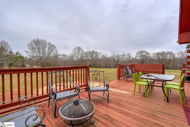 wooden terrace featuring outdoor dining area and a yard