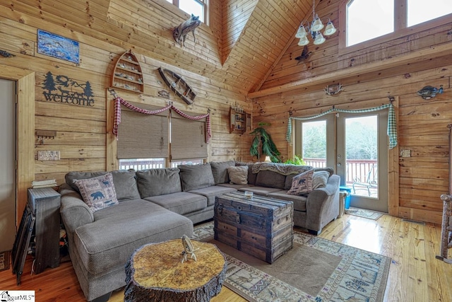 living area featuring wooden walls, french doors, wood-type flooring, and high vaulted ceiling