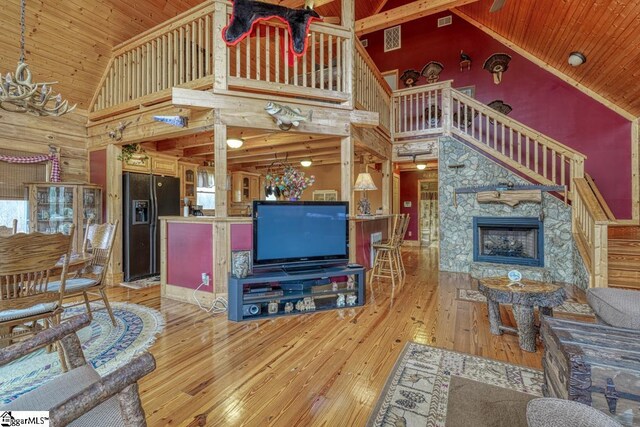 living area featuring hardwood / wood-style floors, wooden walls, high vaulted ceiling, a fireplace, and wooden ceiling