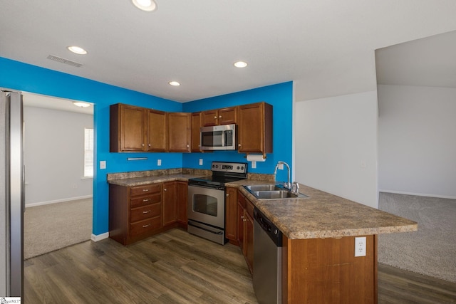 kitchen with visible vents, a peninsula, a sink, stainless steel appliances, and brown cabinets