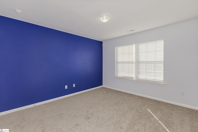 carpeted spare room featuring baseboards