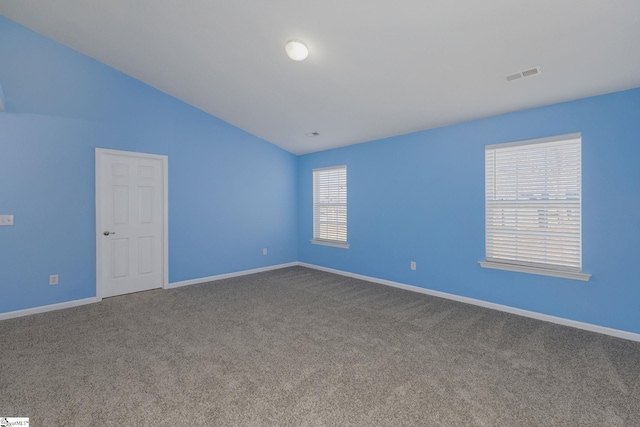 empty room featuring visible vents, baseboards, carpet flooring, and vaulted ceiling