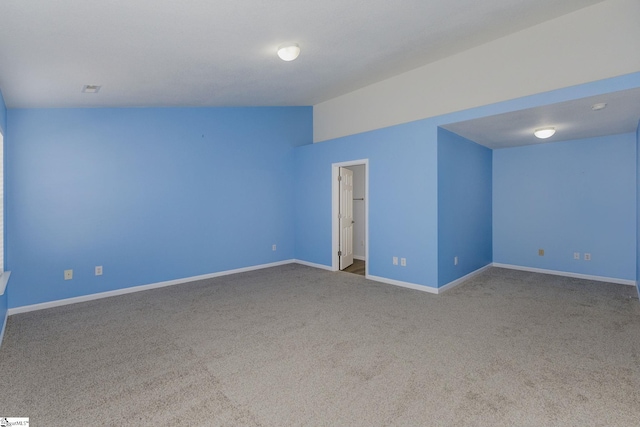 empty room with vaulted ceiling, carpet, and baseboards