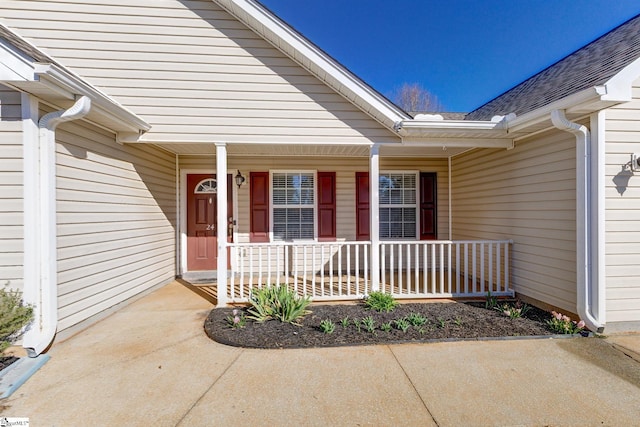 entrance to property featuring roof with shingles and a porch