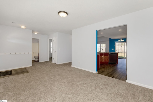 unfurnished room with recessed lighting, baseboards, dark carpet, and a sink