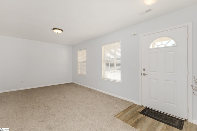 foyer with visible vents, light wood-style flooring, light colored carpet, and baseboards