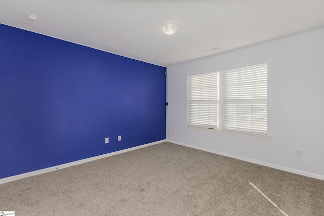 spare room featuring baseboards and carpet floors