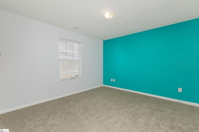 carpeted spare room with visible vents and baseboards