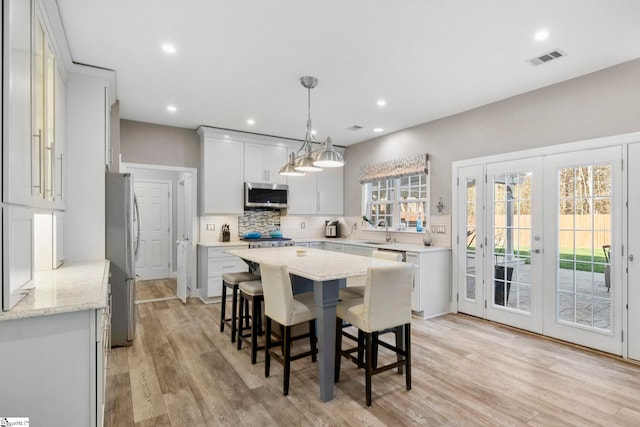 kitchen featuring visible vents, a sink, tasteful backsplash, a center island, and stainless steel appliances