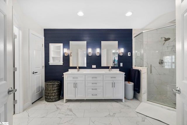 full bath with a sink, marble finish floor, a shower stall, and double vanity