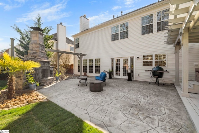 back of house with a fireplace, a patio area, french doors, and a chimney