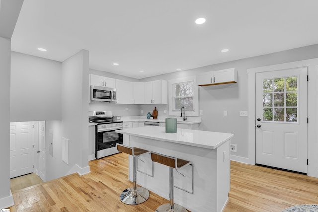 kitchen with plenty of natural light, light wood-style floors, appliances with stainless steel finishes, and white cabinetry