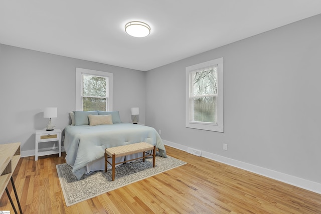 bedroom featuring baseboards, multiple windows, and wood finished floors