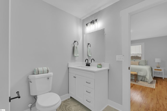 bathroom featuring toilet, vanity, baseboards, and wood finished floors