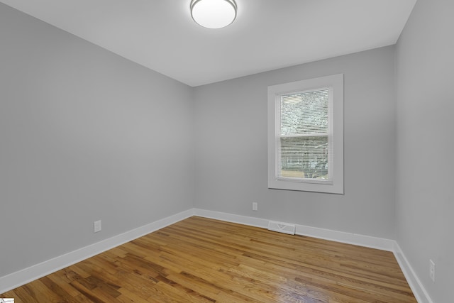 empty room featuring visible vents, baseboards, and wood finished floors